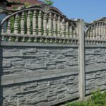long gray stone fence in green grass outside
